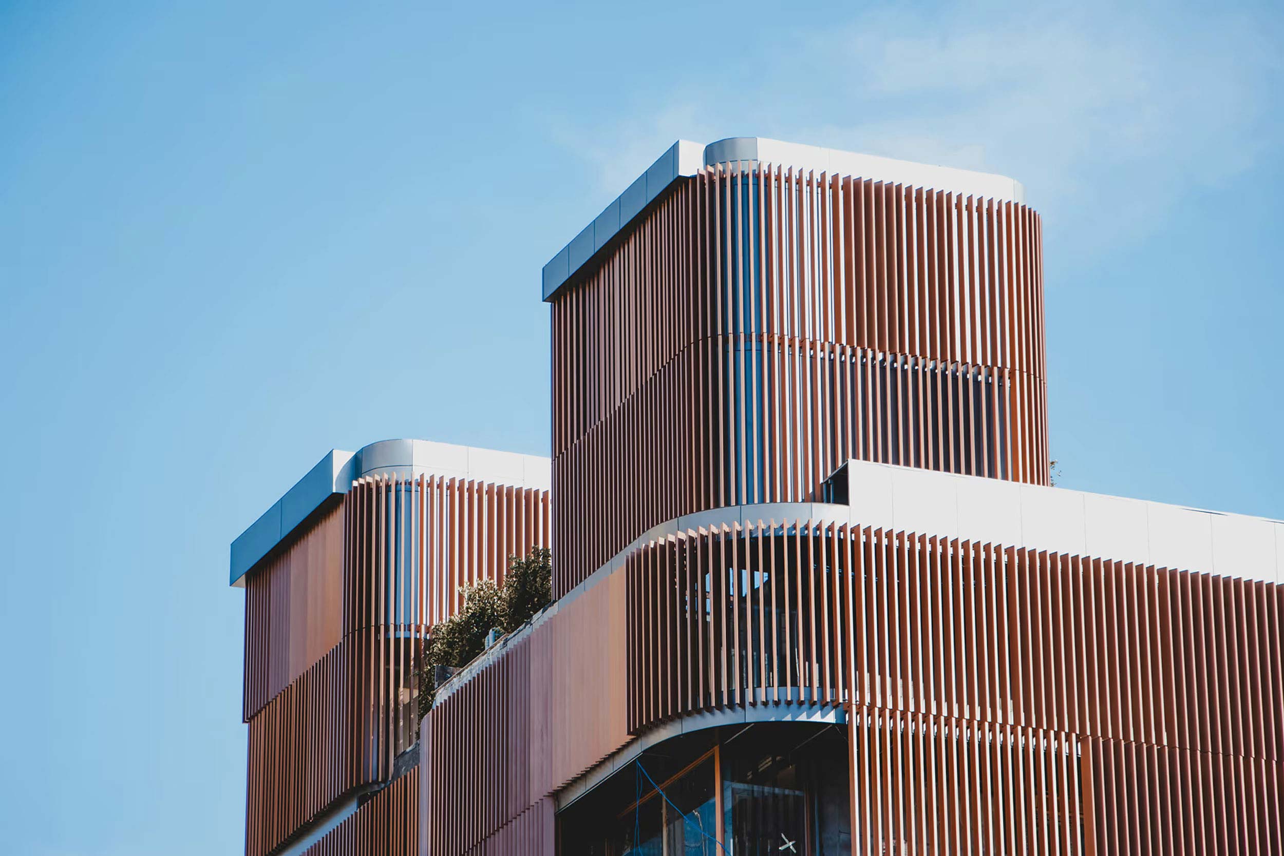 Sleek curved building with expansive glass windows, reflecting the sky and cityscape.